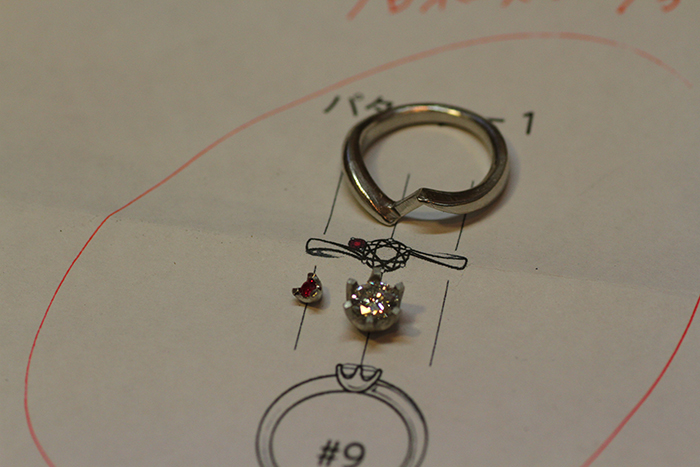 写真：制作途中の婚約指輪をデザイン画と共に。
